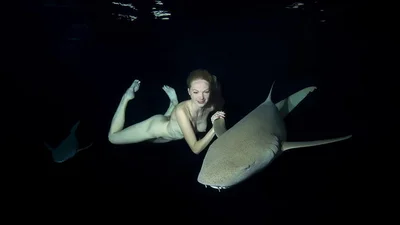 Приголомшливі кадри: оголена модель плаває з акулами